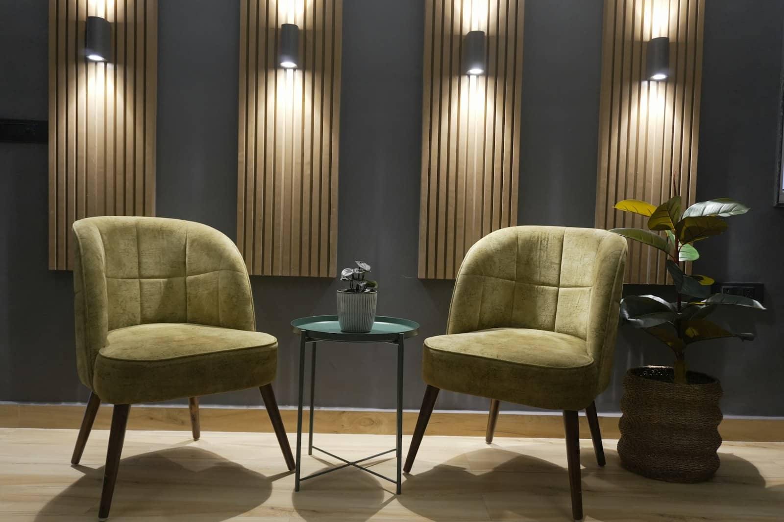 The studio's waiting lounge — sage velvet chairs, warm wood, soft lamplight