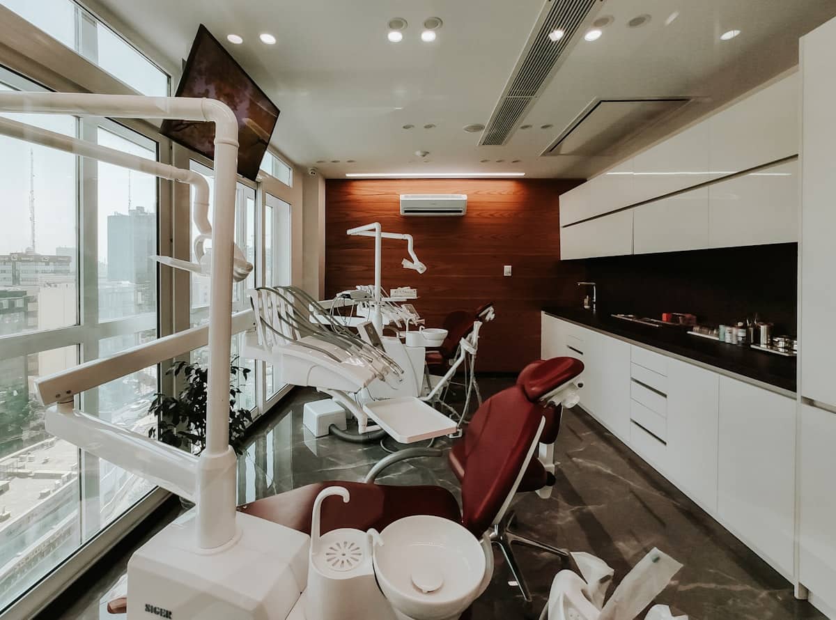 Warm, wood-toned dental treatment room with modern chairs and big windows