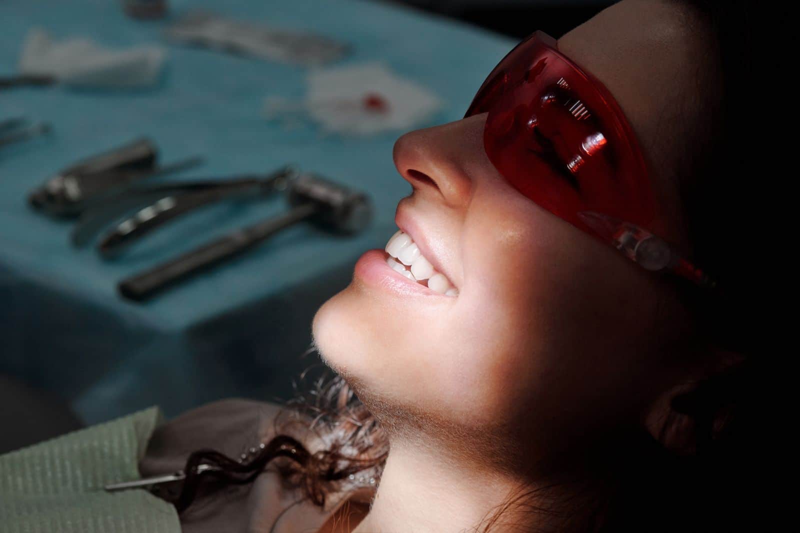 Patient in a dental chair wearing protective glasses, smiling with relief during treatment